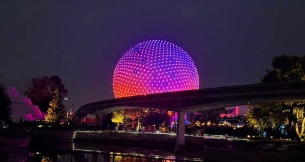 Spaceship Earth glowing with colorful lights at Epcot, Walt Disney World at night.