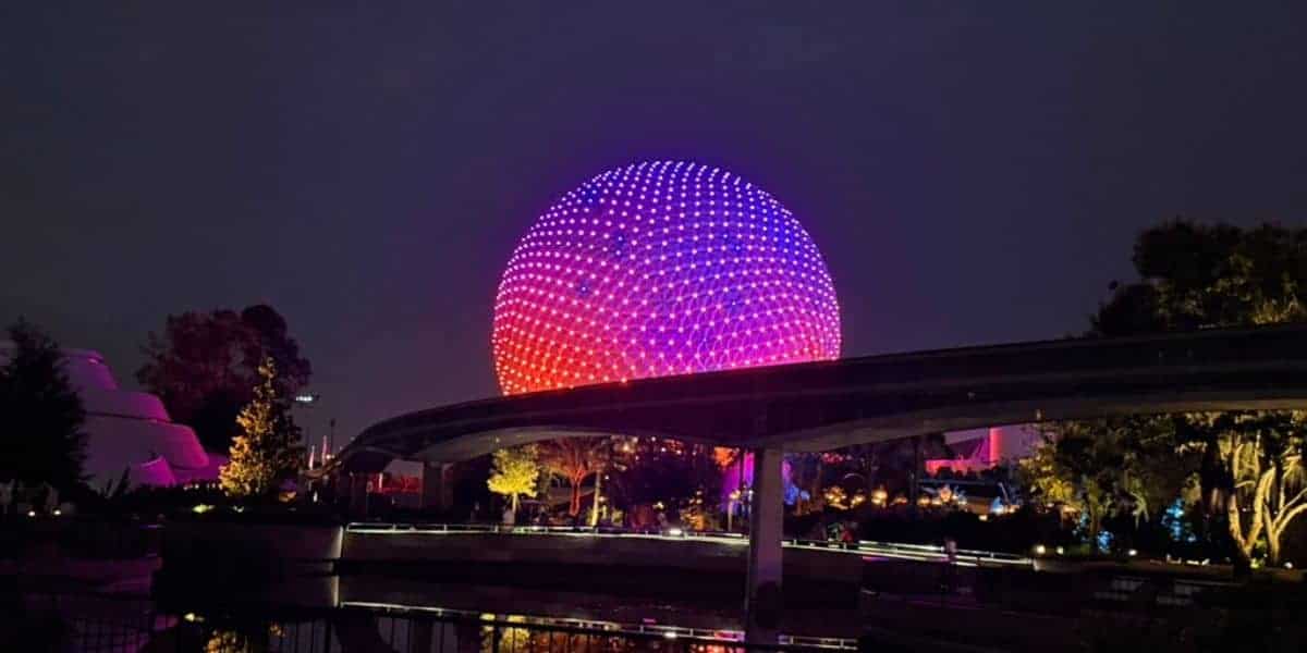 Spaceship Earth glowing with colorful lights at Epcot, Walt Disney World at night.