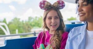 Two guests wearing Minnie Mouse ears ride the Tomorrowland Transit Authority PeopleMover at Magic Kingdom during 2026 travel warnings.
