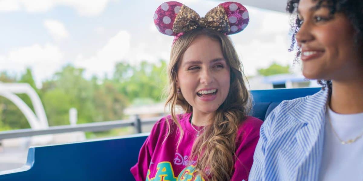 Two guests wearing Minnie Mouse ears ride the Tomorrowland Transit Authority PeopleMover at Magic Kingdom during 2026 travel warnings.
