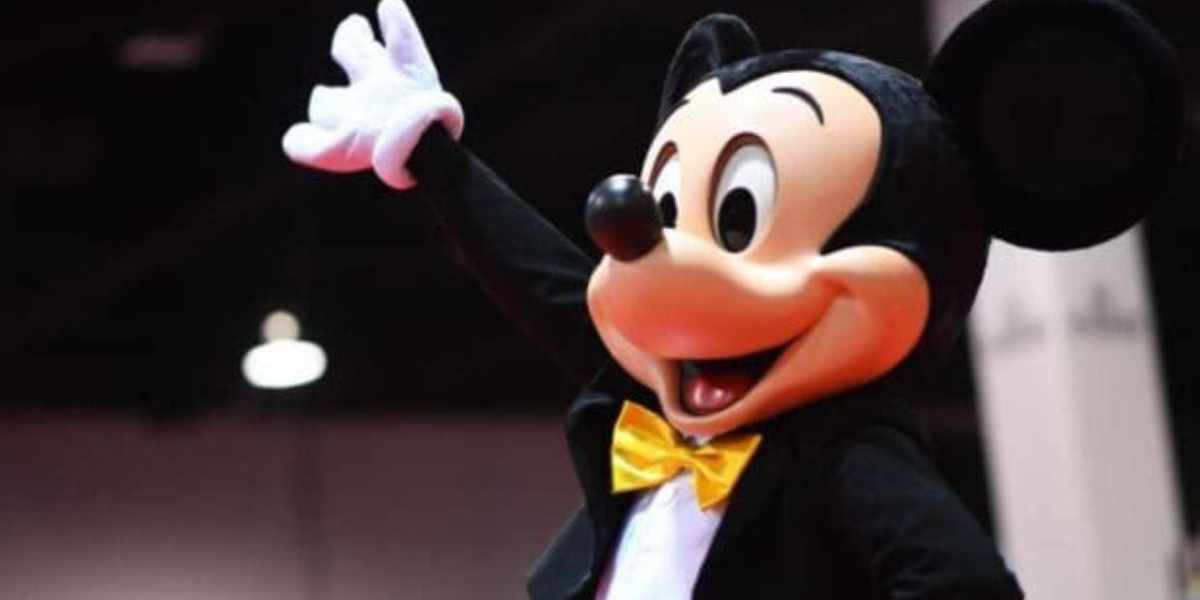Mickey Mouse waving in a tuxedo at Disney World.