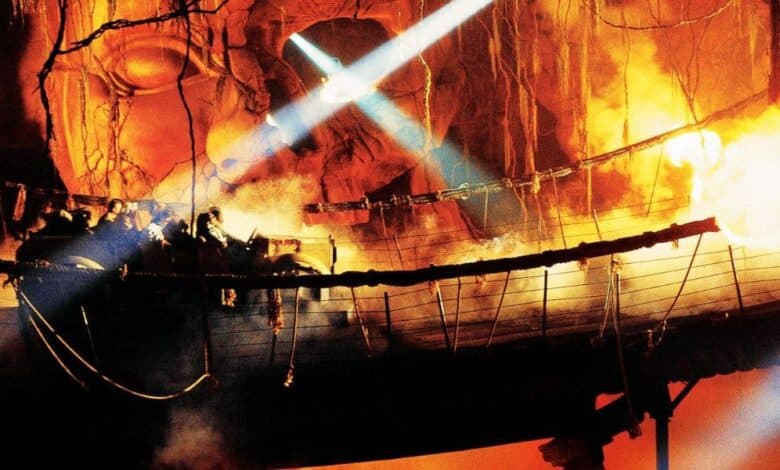 An Indiana Jones Adventure ride vehicle crosses the rope bridge amid fire effects.