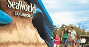 Family walking past the SeaWorld San Antonio entrance sign.