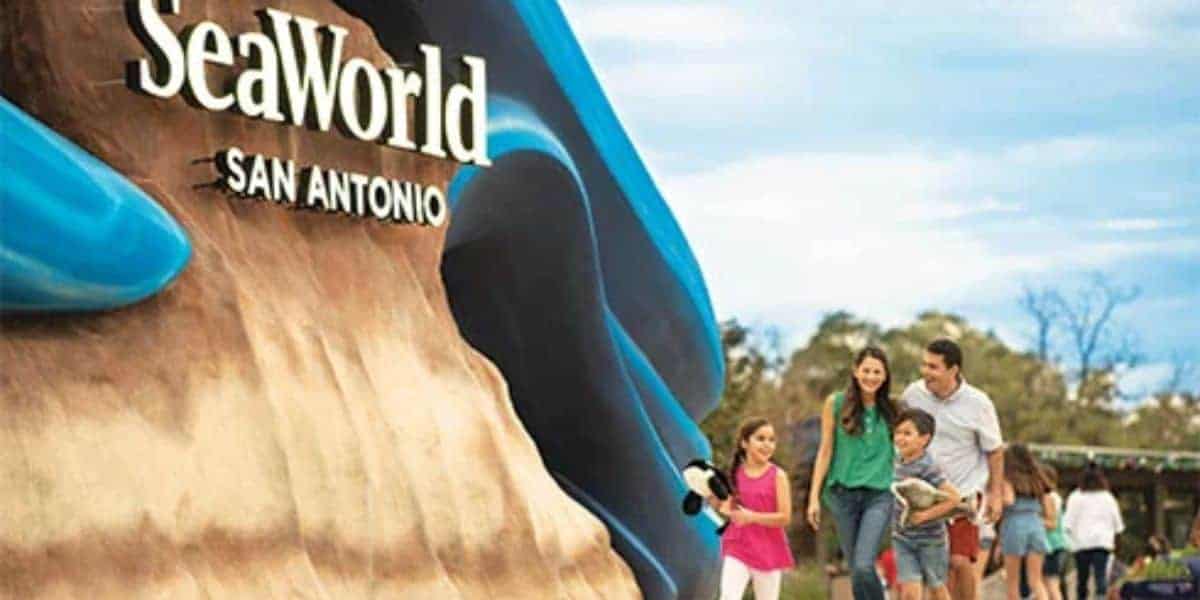 Family walking past the SeaWorld San Antonio entrance sign.