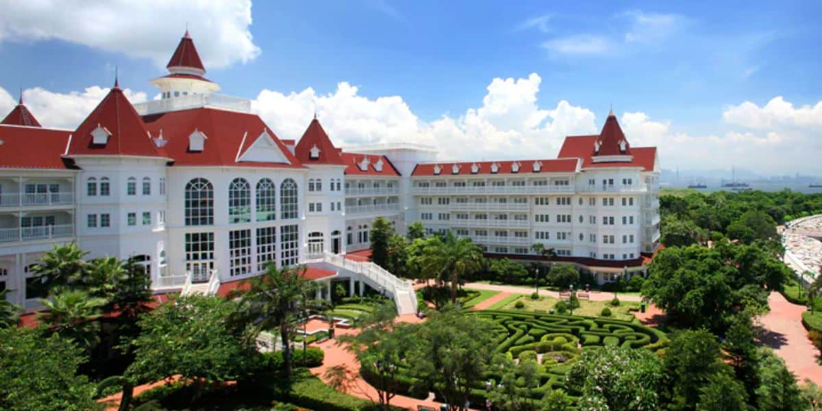 Aerial view of the Hong Kong Disneyland Hotel, featuring its signature garden maze and Victorian-style white buildings with red roofs.