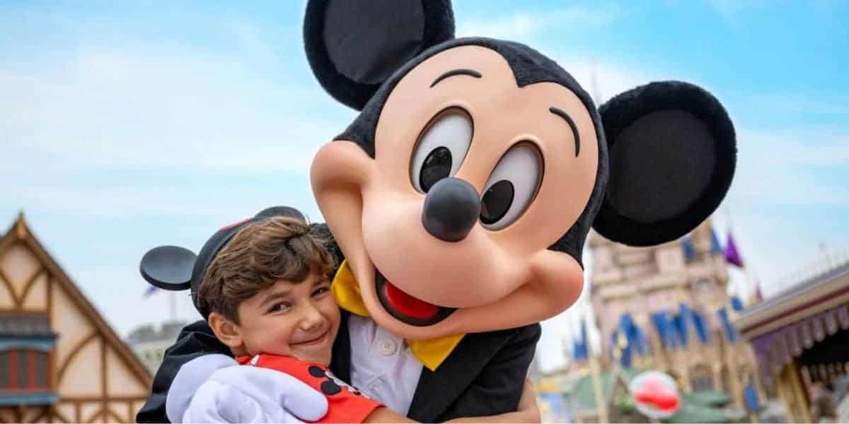A young boy hugs Mickey Mouse at Disney World.