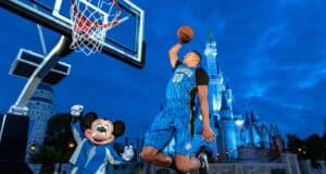 Orlando Magic forward Aaron Gordon dunks a basketball as Mickey Mouse cheers at Disney World in front of Cinderella Castle.