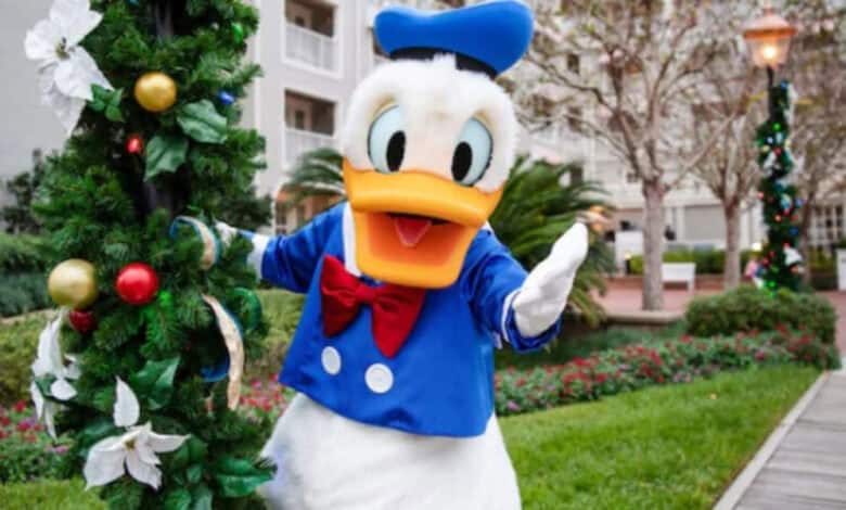 Donald Duck posing by a Christmas tree at Disney’s Beach Club Resort for a Disney holiday special.