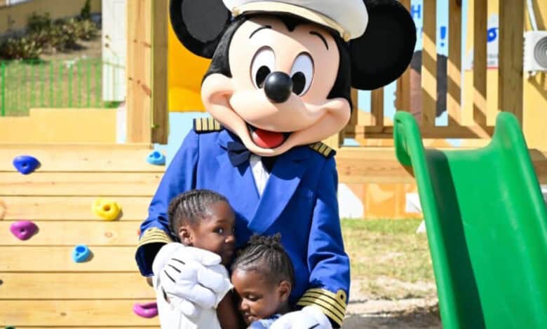 Captain Mickey Mouse hugging two children aboard a Disney Cruise Line ship.