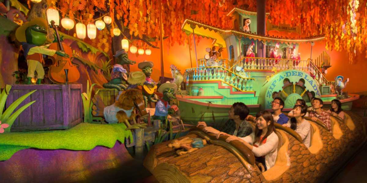 Guests in a log boat float past the Zip-A-Dee Lady showboat at Tiana’s Bayou Adventure.