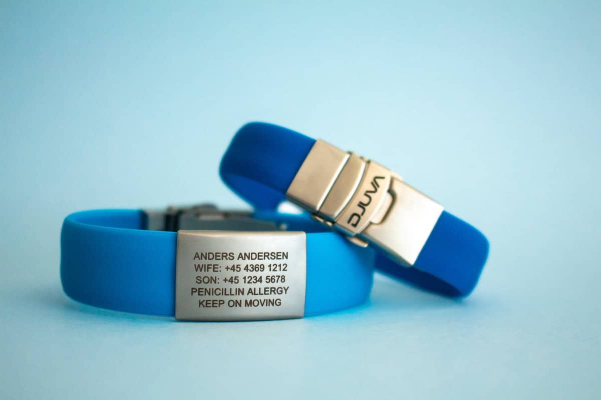 DJUVA Beat ID armbånd: Blåt silikone ID-armbånd med indgraveret informationsplade og sølvspænde. Perfekt til medicinsk information.