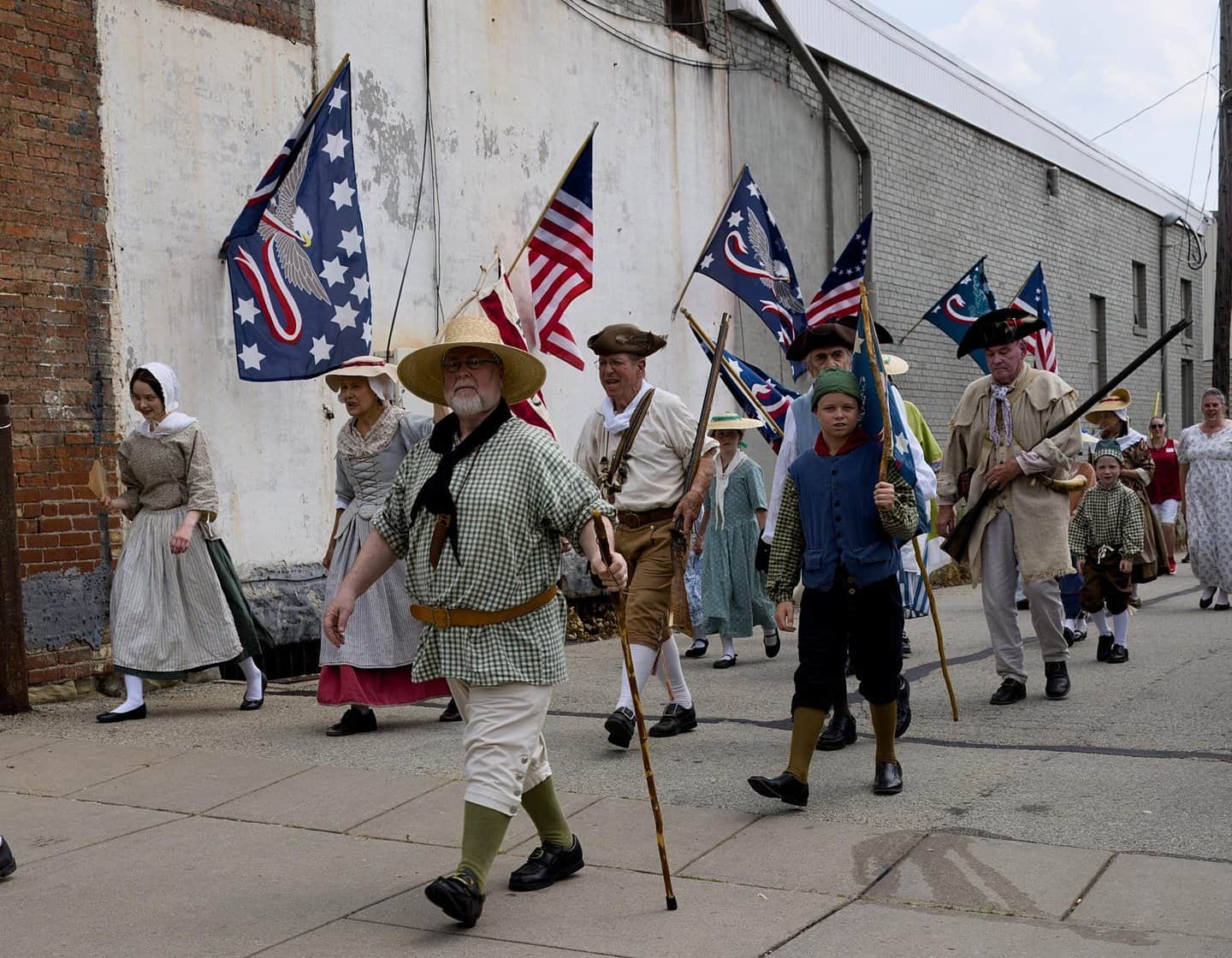 Group of people dressed in historical costumes with American flags in downtown Washington, PA.