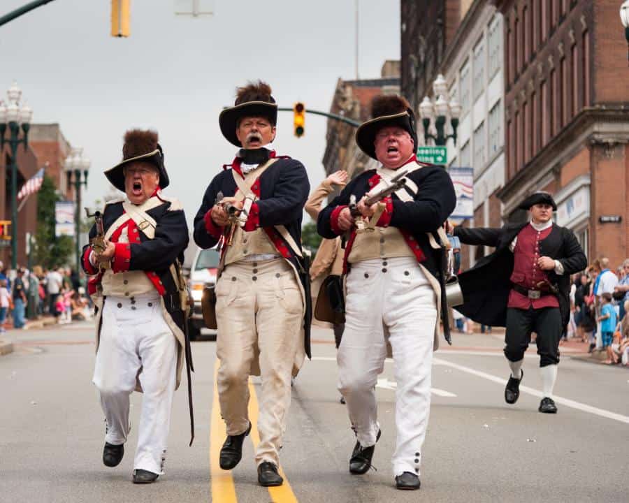Reenactors dressed in 18th-century military costumes walking through downtown Washington, Pennsylvan.