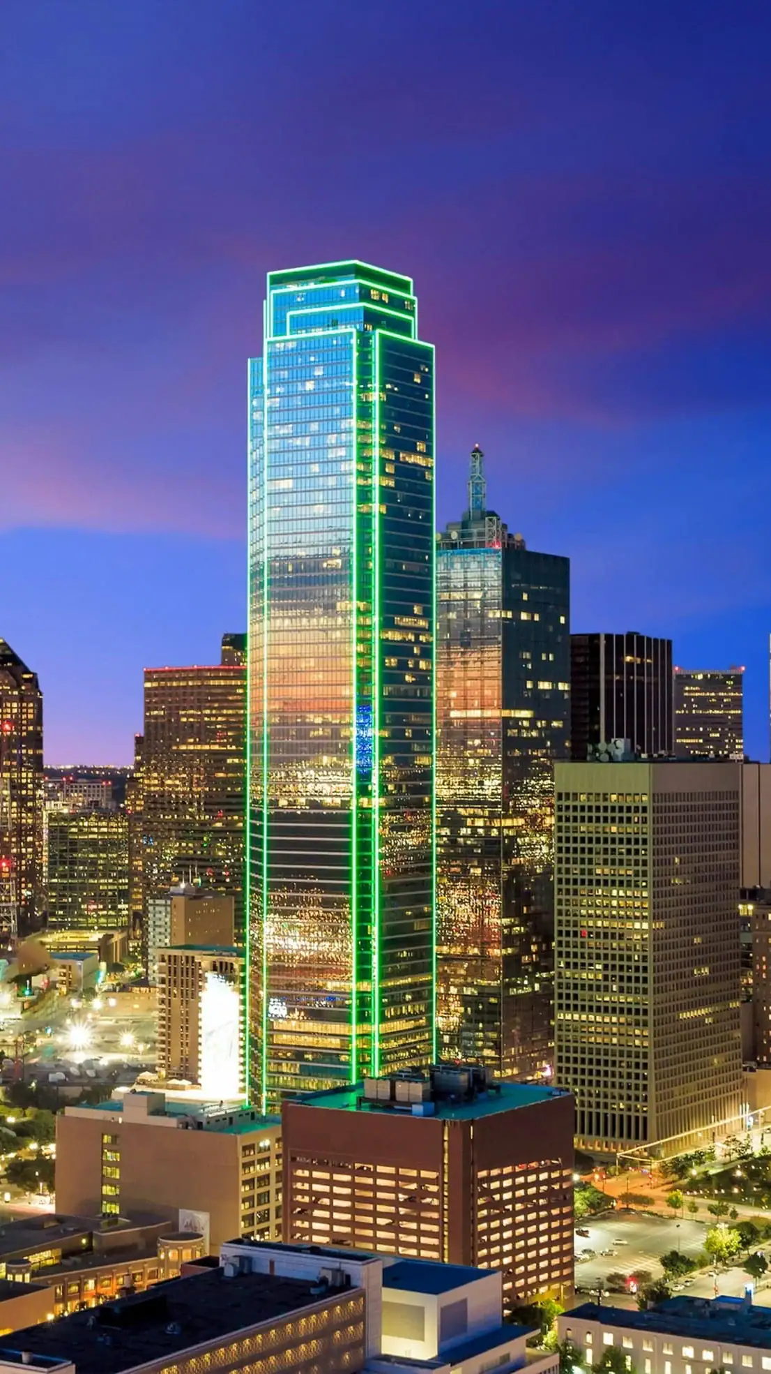 Modern downtown skyscraper illuminated at night with vibrant city lights.