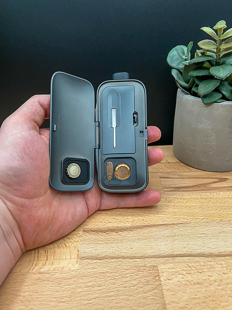 AirVape Legacy Pro 2 clamshell design open to show heating chamber, stirring tool, and magnetic airflow screen✍️ CaptionThe clamshell opens clean—Legacy Pro 2 reveals its chamber, stir tool, and magnetic screen in full view.📘 DescriptionA high-resolution close-up of the AirVape Legacy Pro 2 with its signature clamshell design fully open. The image clearly displays the ceramic heating chamber, the built-in stirring tool nestled inside the lid, and the magnetic screen filter used for airflow refinement. Shot on a rustic wood surface with soft ambient lighting, this layout emphasizes the device’s modular architecture and thoughtful engineering—perfect for educating readers about its internal features and maintenance-friendly design.Let me know if you'd like variations geared toward gallery schema, Pinterest optimization, or YouTube metadata. Ready when you are for the next one. 🔄📸