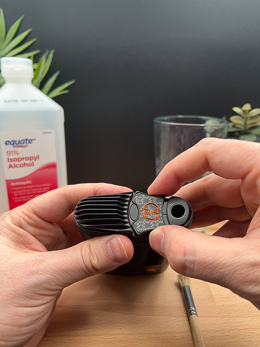 Hands holding the top cooling unit of a Mighty+ vaporizer with visible buildup, preparing for O-ring removal and cleaning.