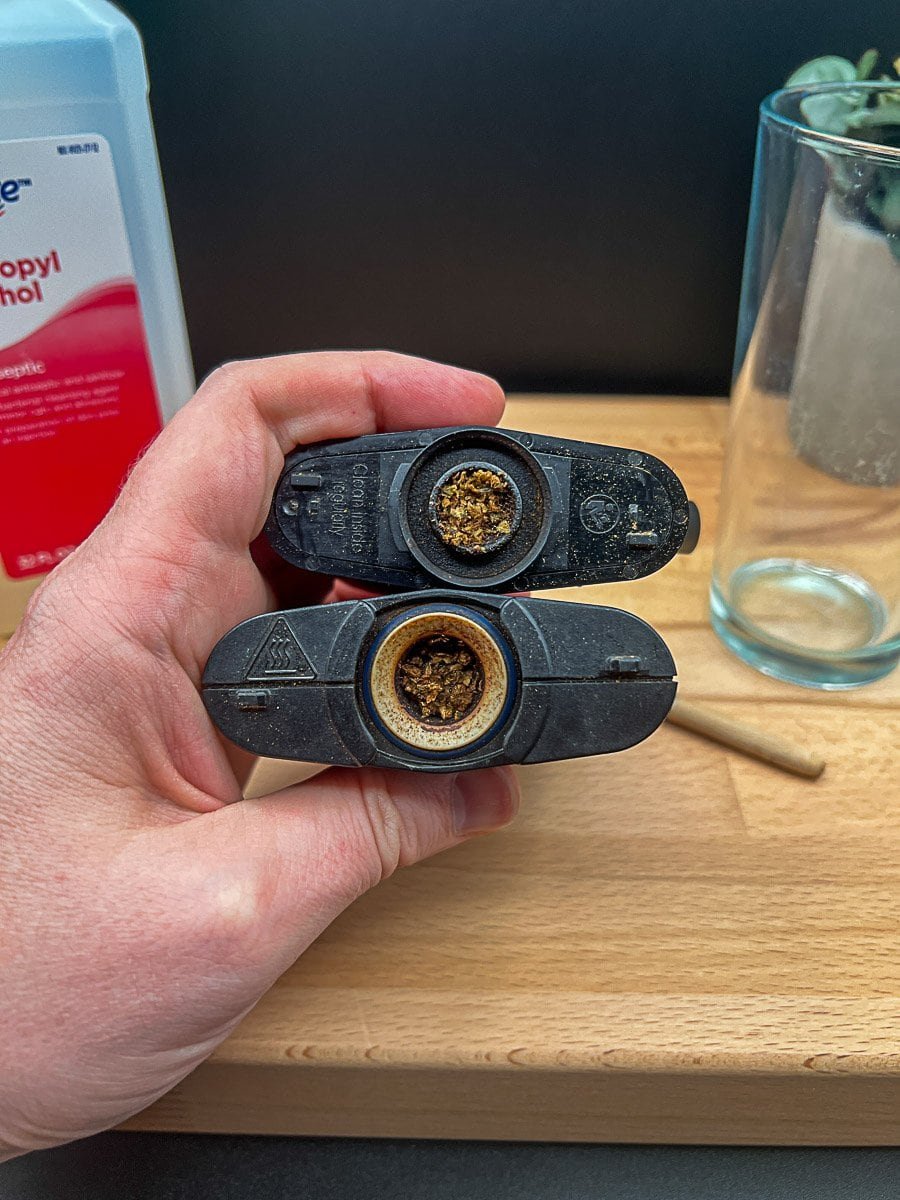 Used Mighty+ vaporizer parts held above a table with isopropyl alcohol and cleaning tools, highlighting buildup and preparation for deep cleaning.