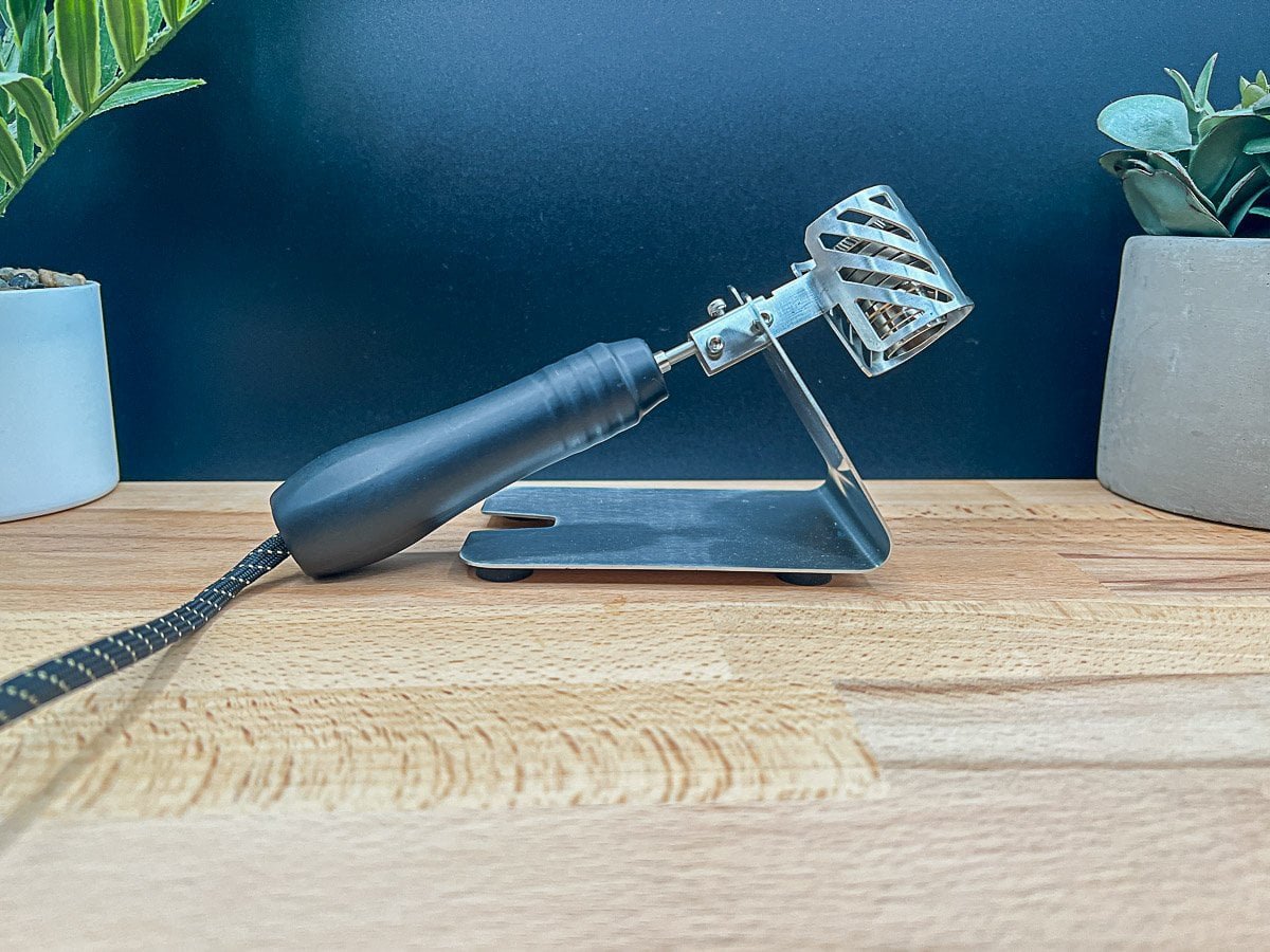 The Ruby Twist ball vape injector head with its black handle resting securely on its metal stand, next to a power cable.