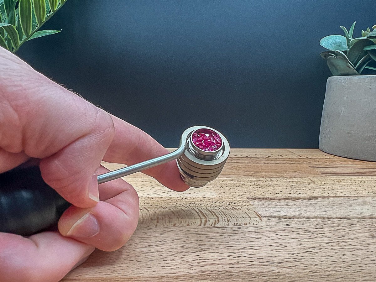 Close-up of a hand holding the Ruby Twist ball vape injector head, clearly showing the red gemstone rubies inside, for a Ruby Twist review 2025.