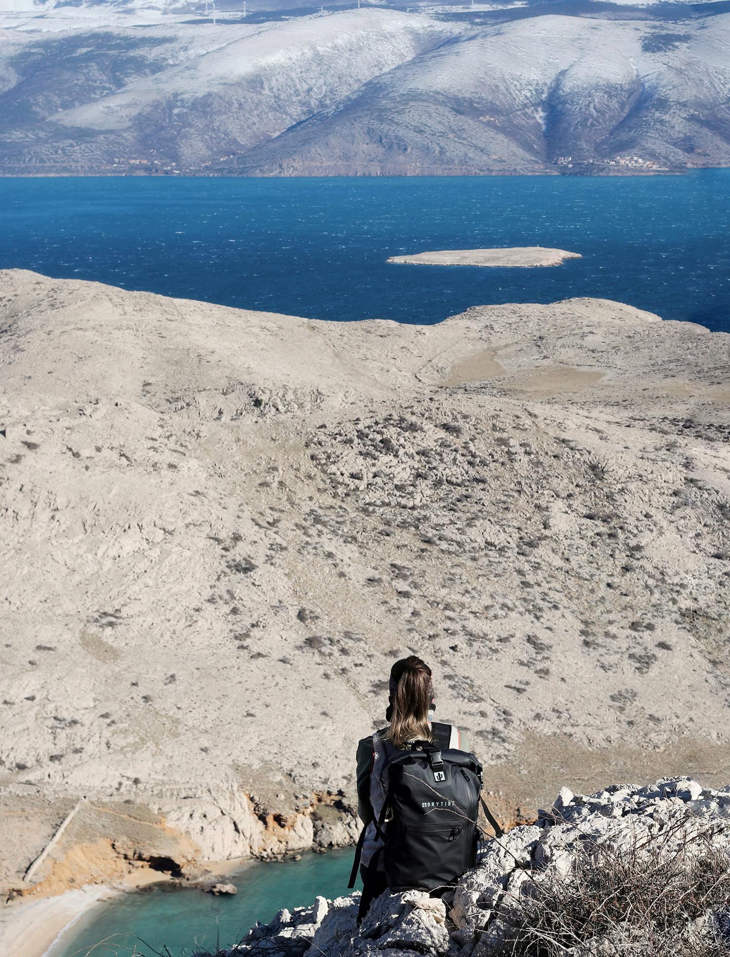 DryTide 30L waterproof backpack with view of the sea and mountains from the hill above the bay