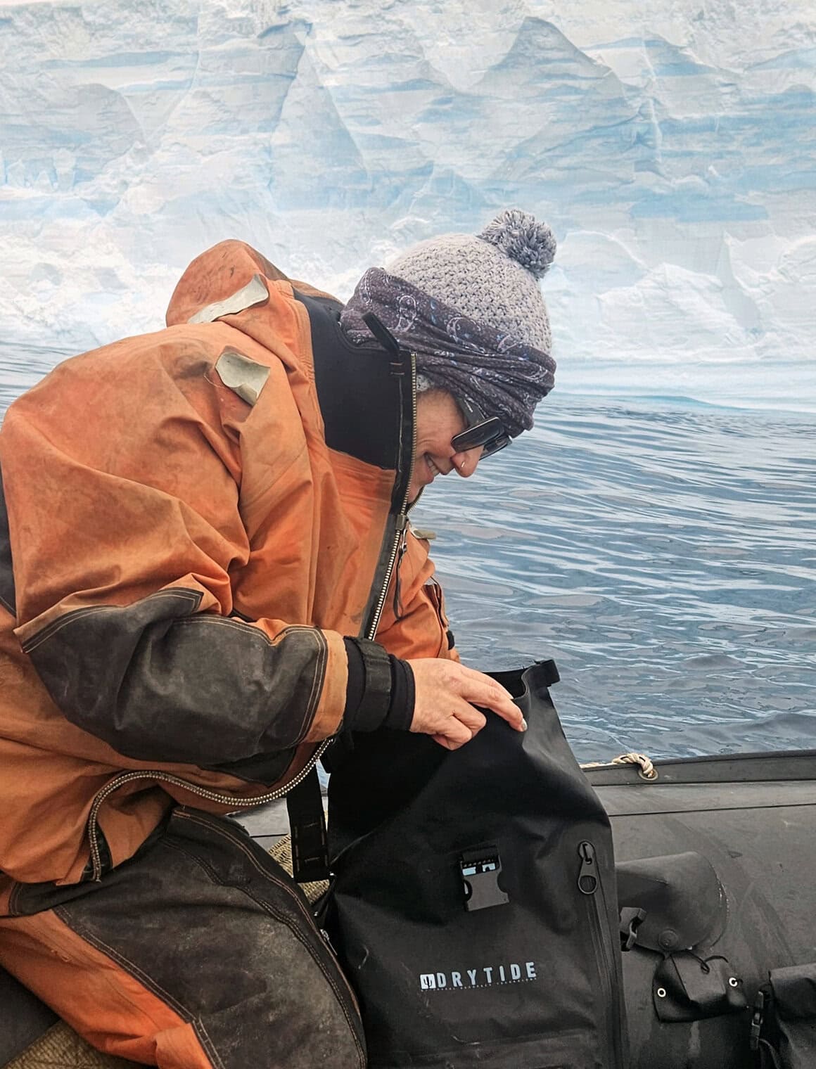 Waterproof backpack in icy outdoor environment with glacier and water background.
