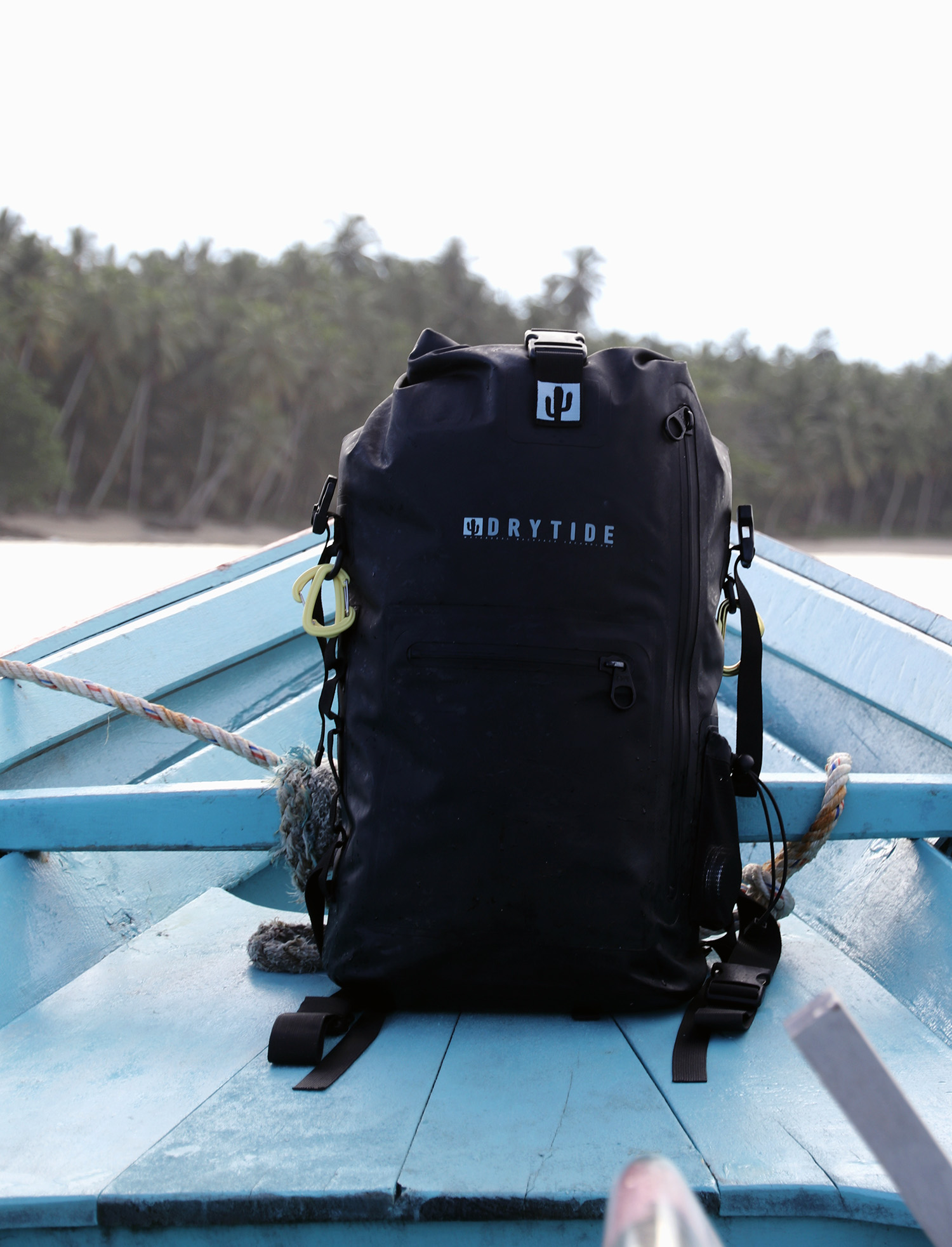 Waterproof backpack on boat deck with water and trees in background, DryTide gear for outdoor advent.