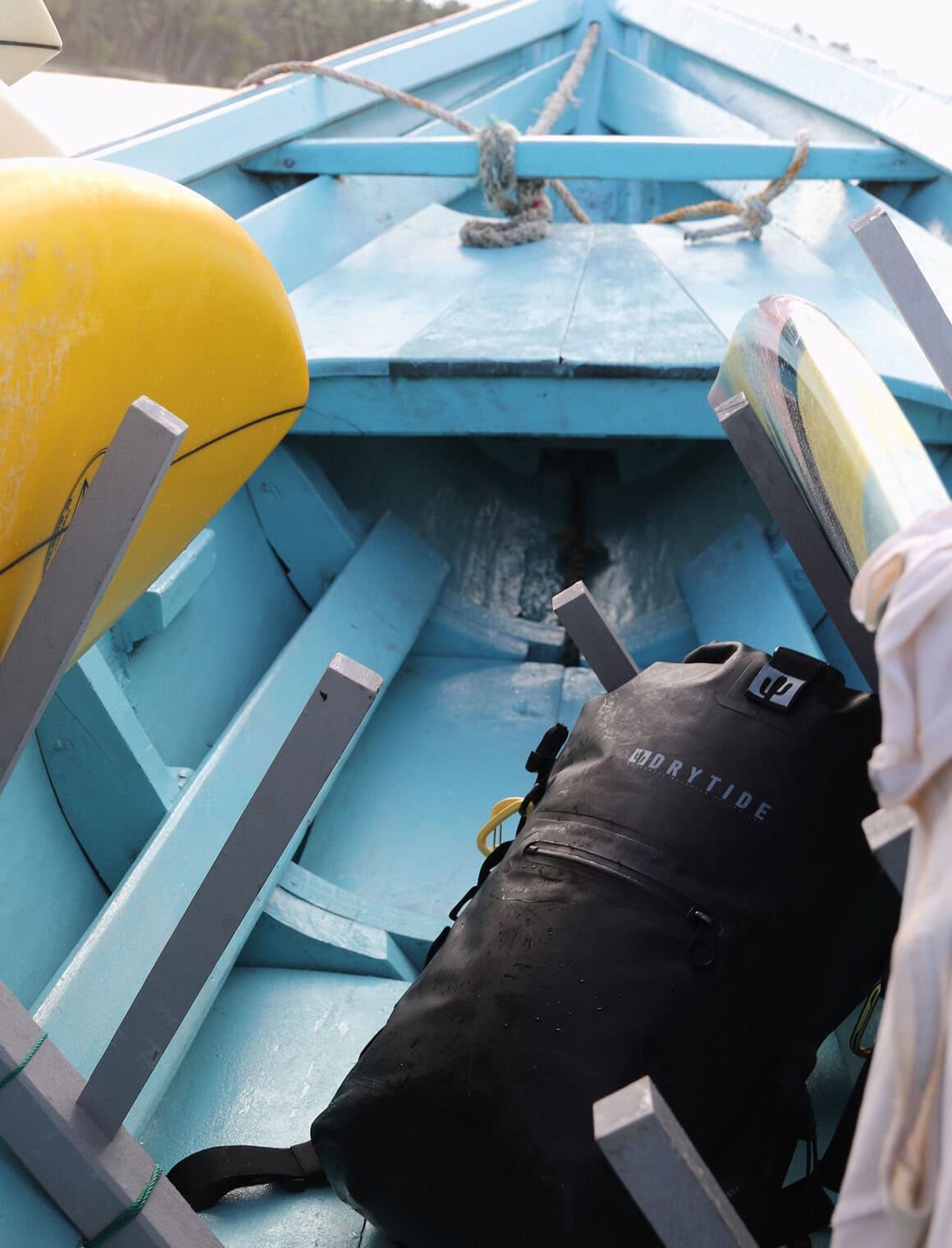 Waterproof backpack on a boat with paddles and safety gear, ideal for water adventures.