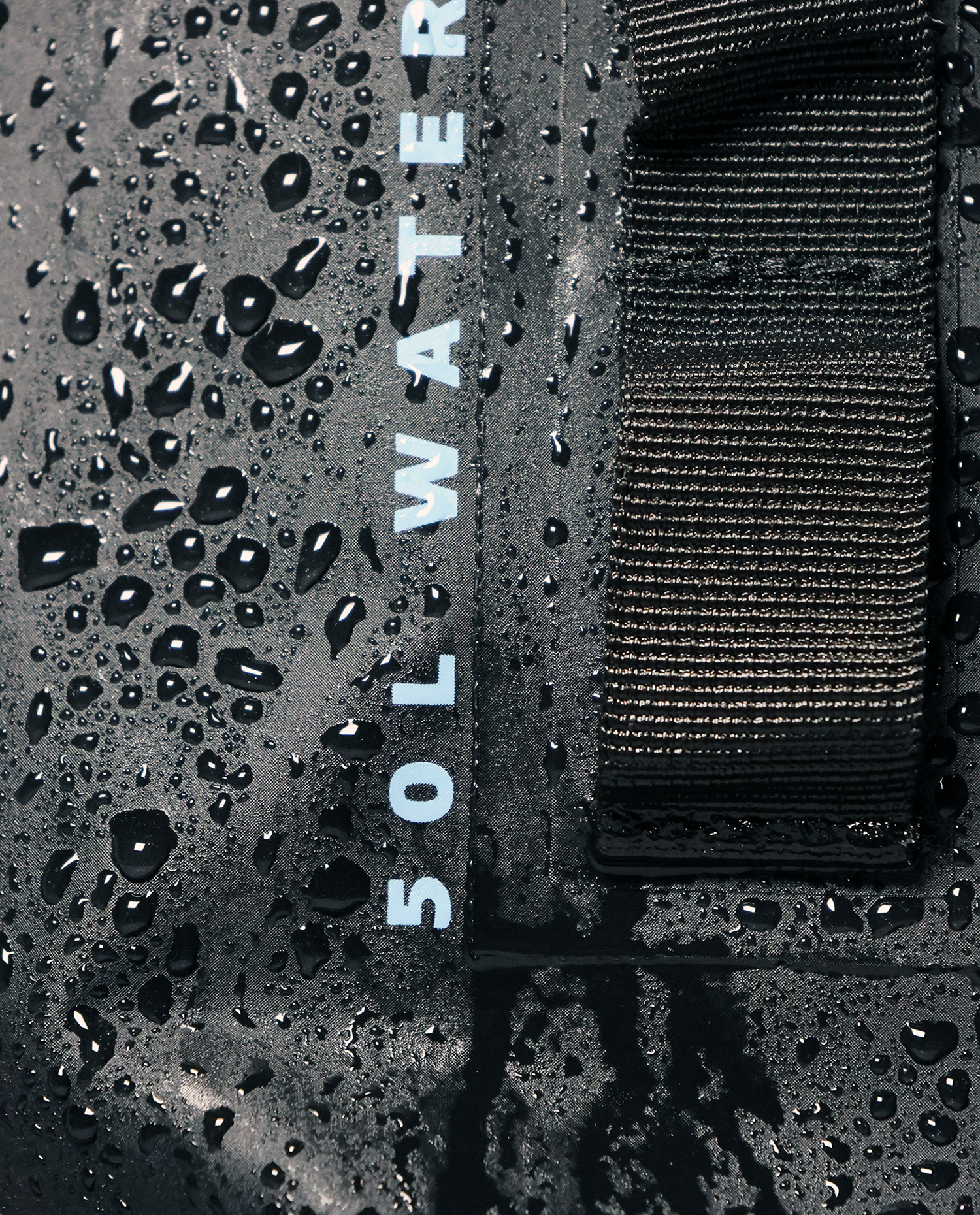 Close-up of waterproof material with water droplets and strap detail.