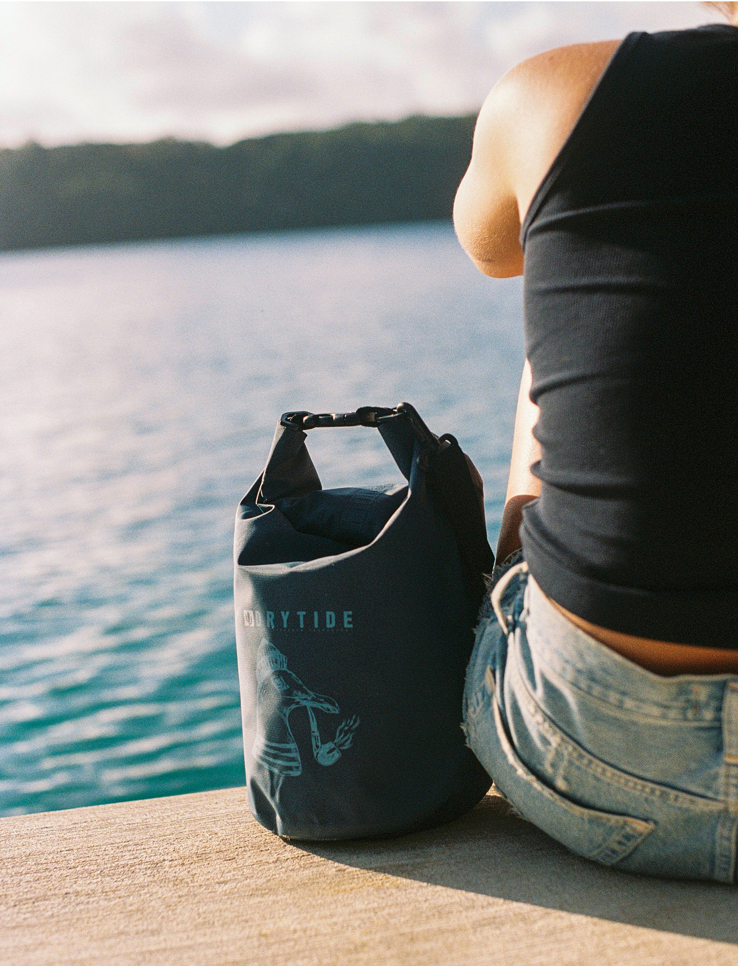 DryTide 5L dry bag Pacific ocean Waterproof dry bag by DRYTIDE next to a person sitting by the water's edge.