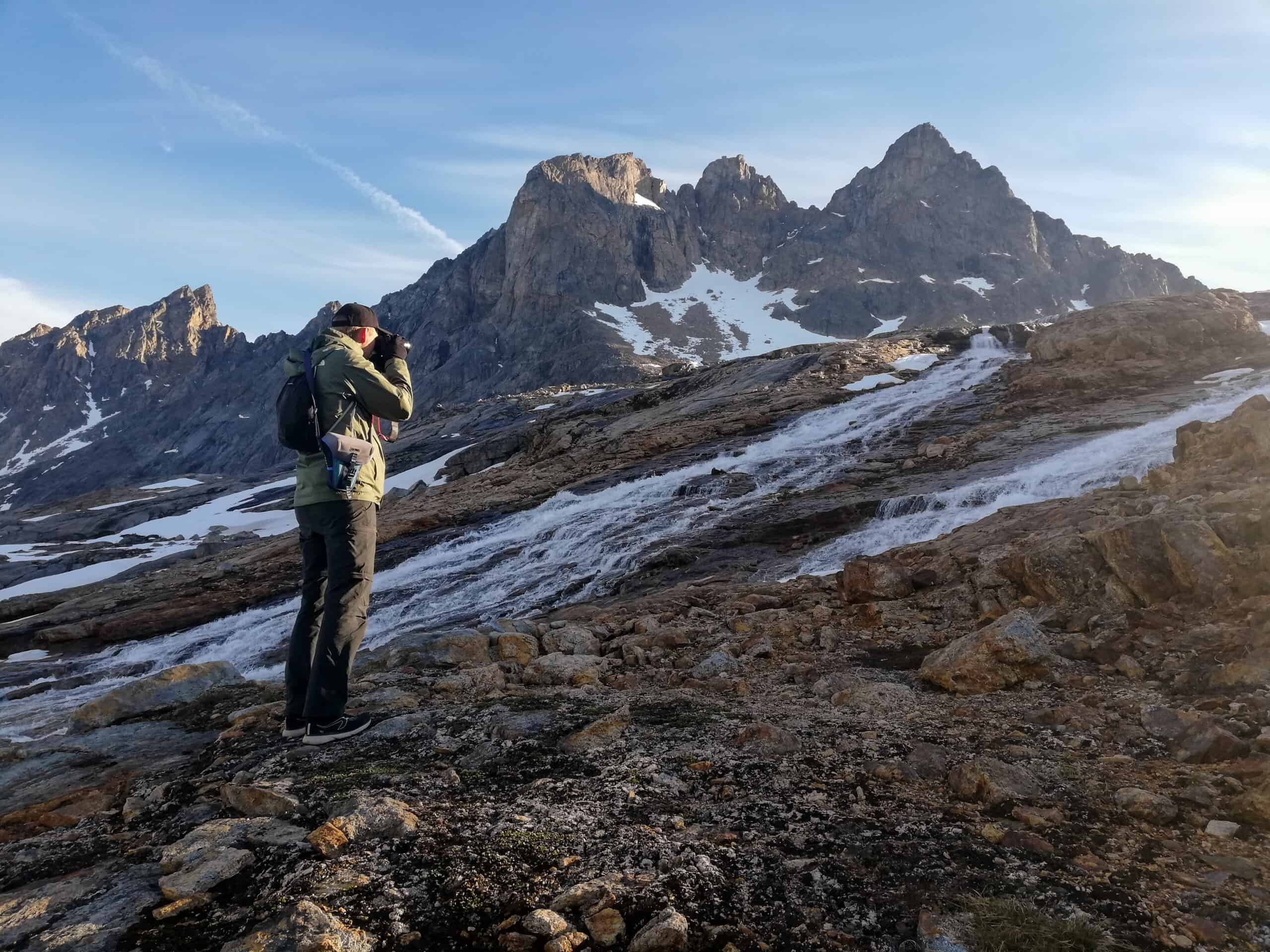 Tourist photographing a waterfall in the backountry of East Greenland.