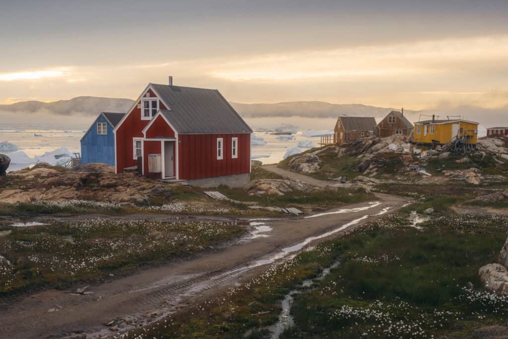 Colourful houses along a gravel road at sunset in East Greenland