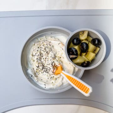 This is a photo of the loaded yogurt bowl in an EZ PZ mat with blueberries and kiwi and a baby spoon.