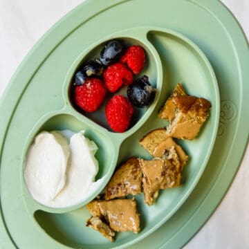 This is a photo of an EZPZ plate with the easy banana pancakes with a side of yogurt and blueberries and raspberries