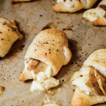 This is a photo of the cinnamon apple and brie crescent rolls on a sheet pan with the focus on the center.