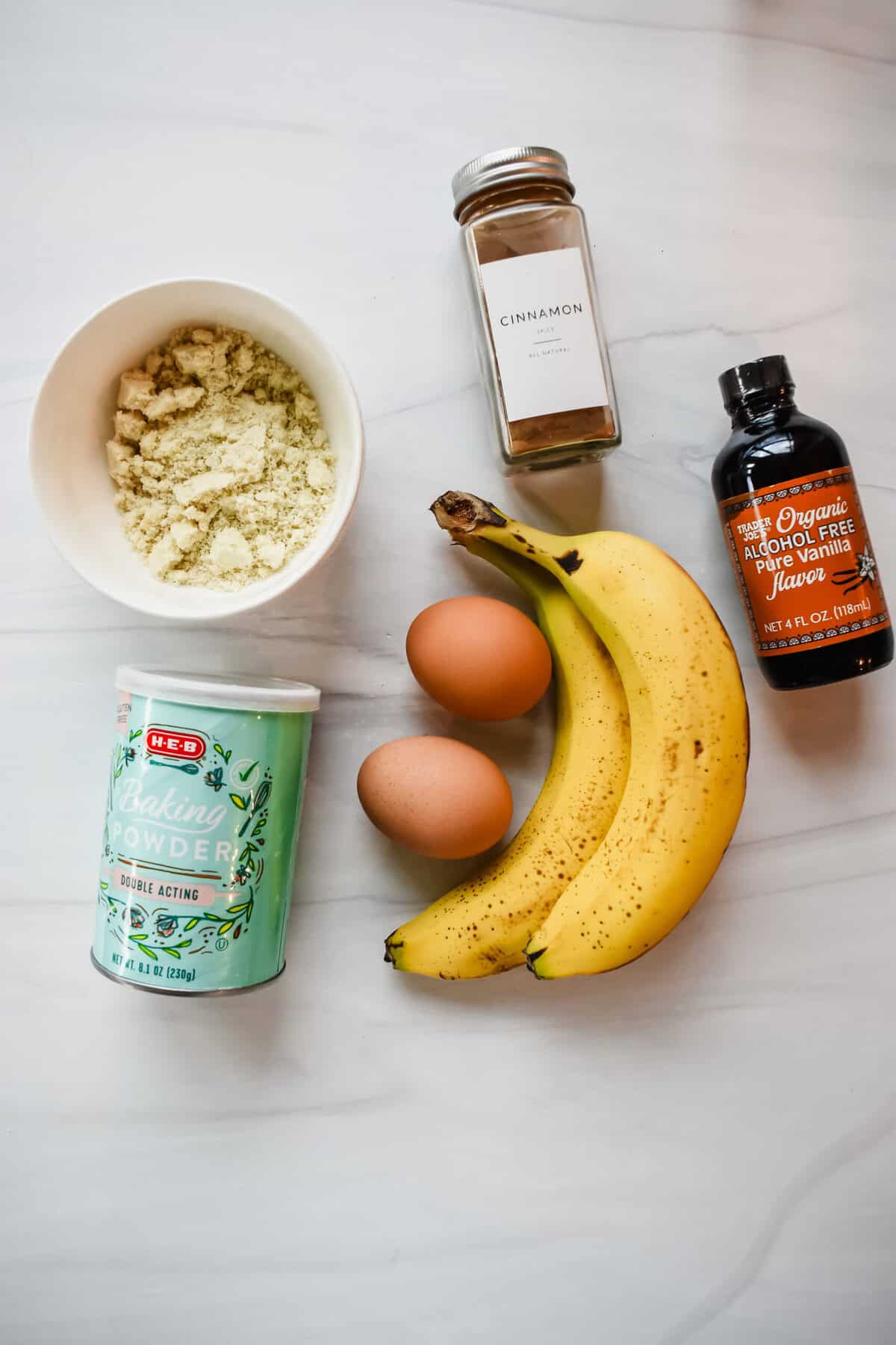 this is a top view of all of the ingredients including almond flour, baking powder, eggs, bananas, vanilla extract and cinnamon