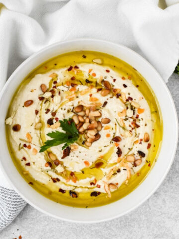 This is an overhead view of the authentic hummus with olive oil, spices and toasted pinenuts on top.