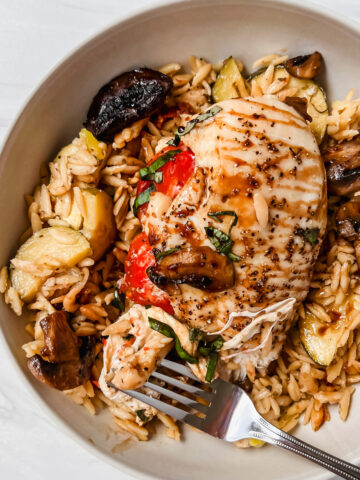 This is a photo of the one pan baked caprese chicken in a plate with mushrooms and over a bed of orzo
