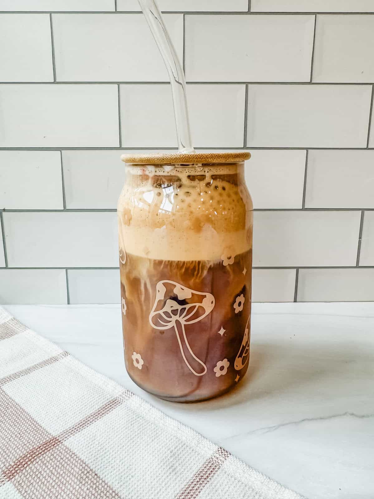 This is a side view close up of my starbucks salted cream cold foam recipe on top of cold brew in a glass mushroom designed cup. 