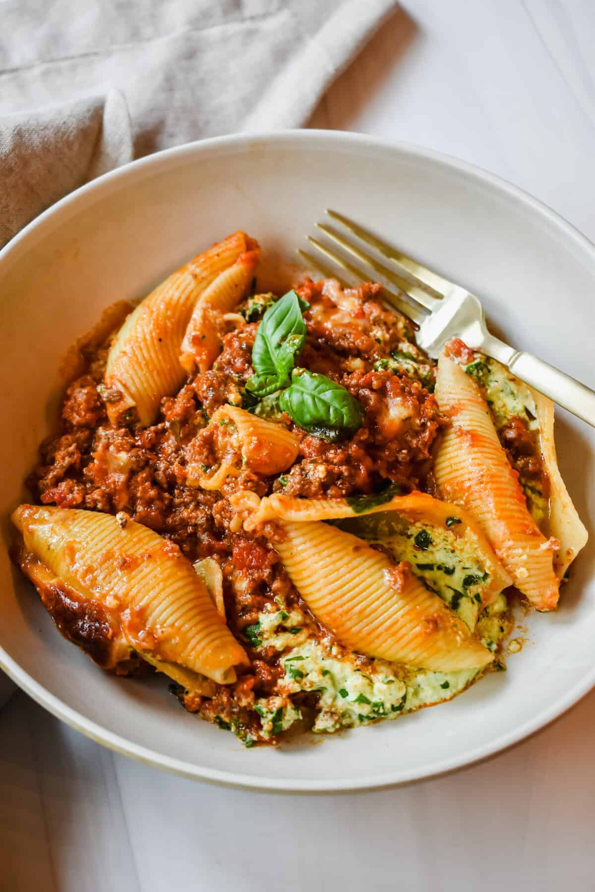 This is a top view close up of my lasagna stuffed shells on a plate with a golden fork.  