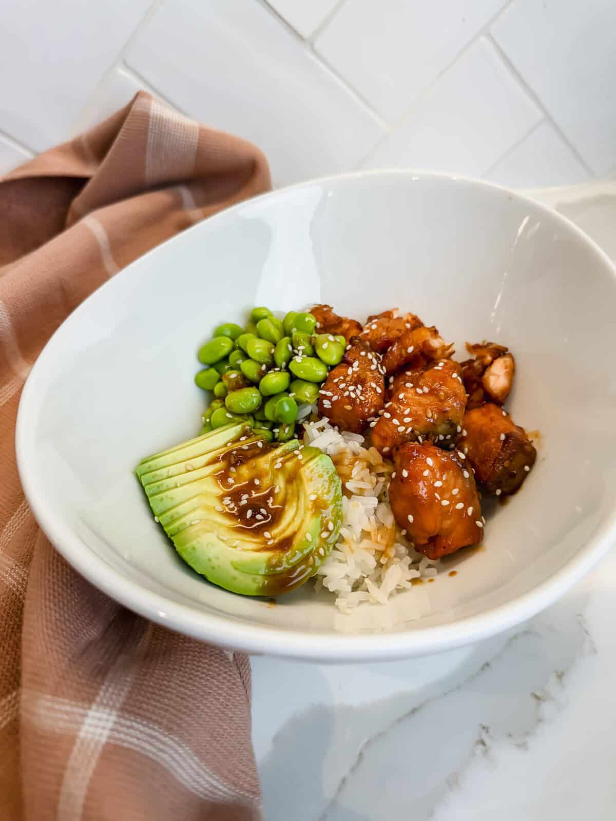 This is a side view of my Trader Joe's Salmon Bite Bowls featuring white rice, edamame, sliced avocado and delicious soyaki salmon bites. 