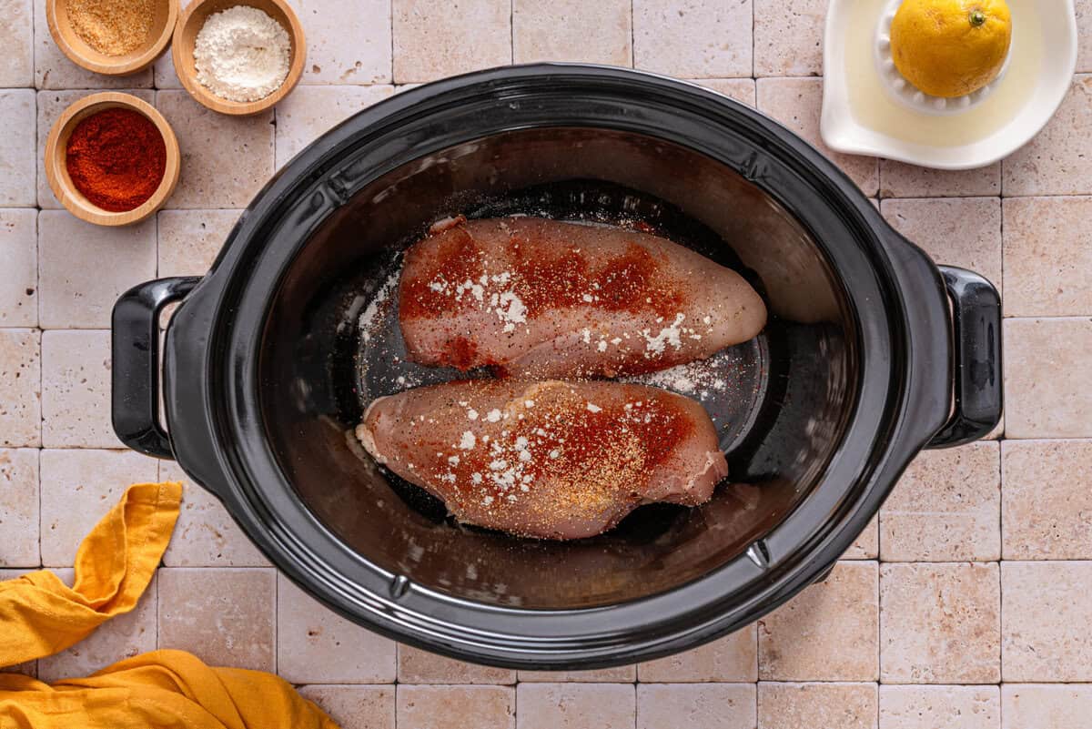 this shows the chicken in the crockpot with the seasonings