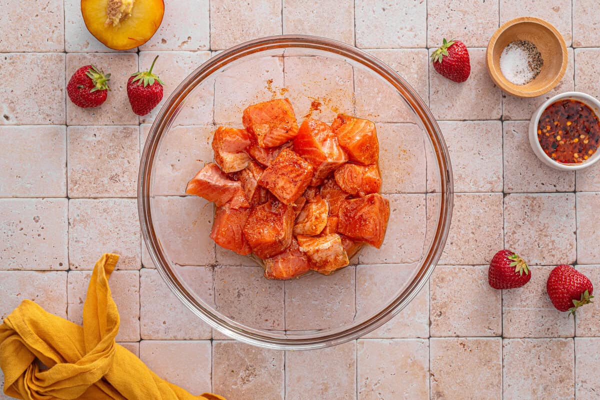 this shows the salmon seasoned and tossed in a bowl 