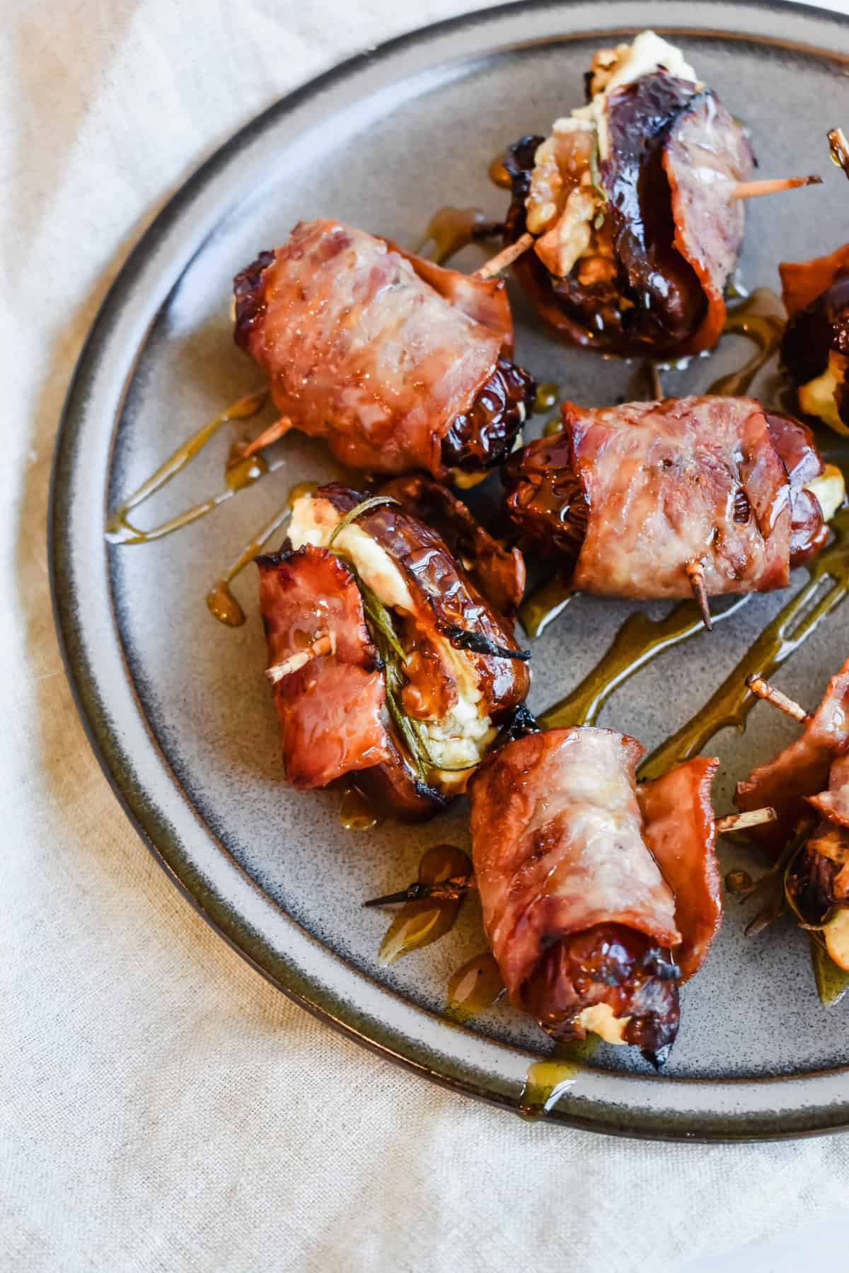 This is a close up of my turkey bacon wraped dates on a plate with hot honey on top.