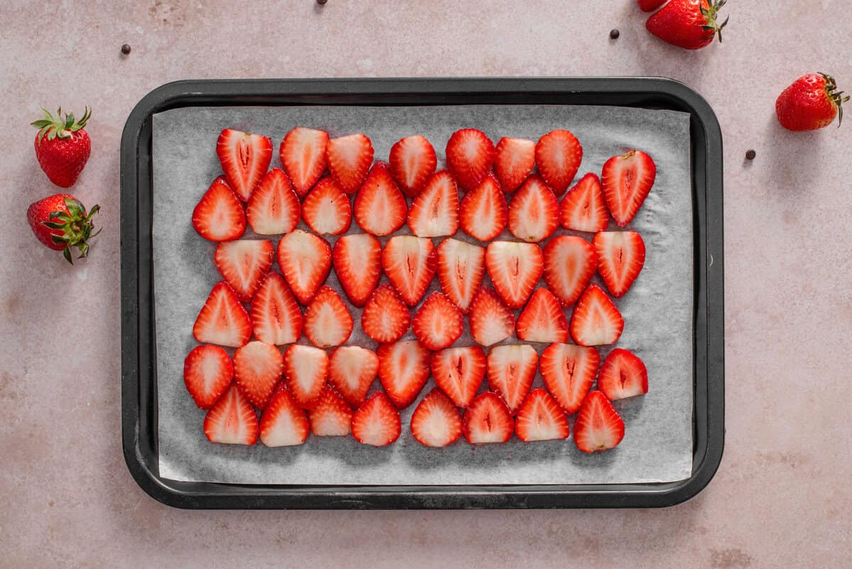 this shows me adding strawberry slices in a layer on parchment lined baking sheet. 