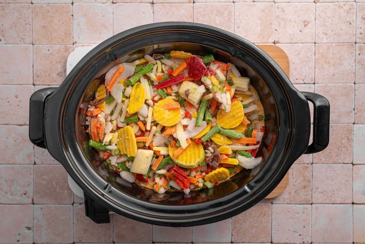 Overhead shot of vegetables added in slow cooker.