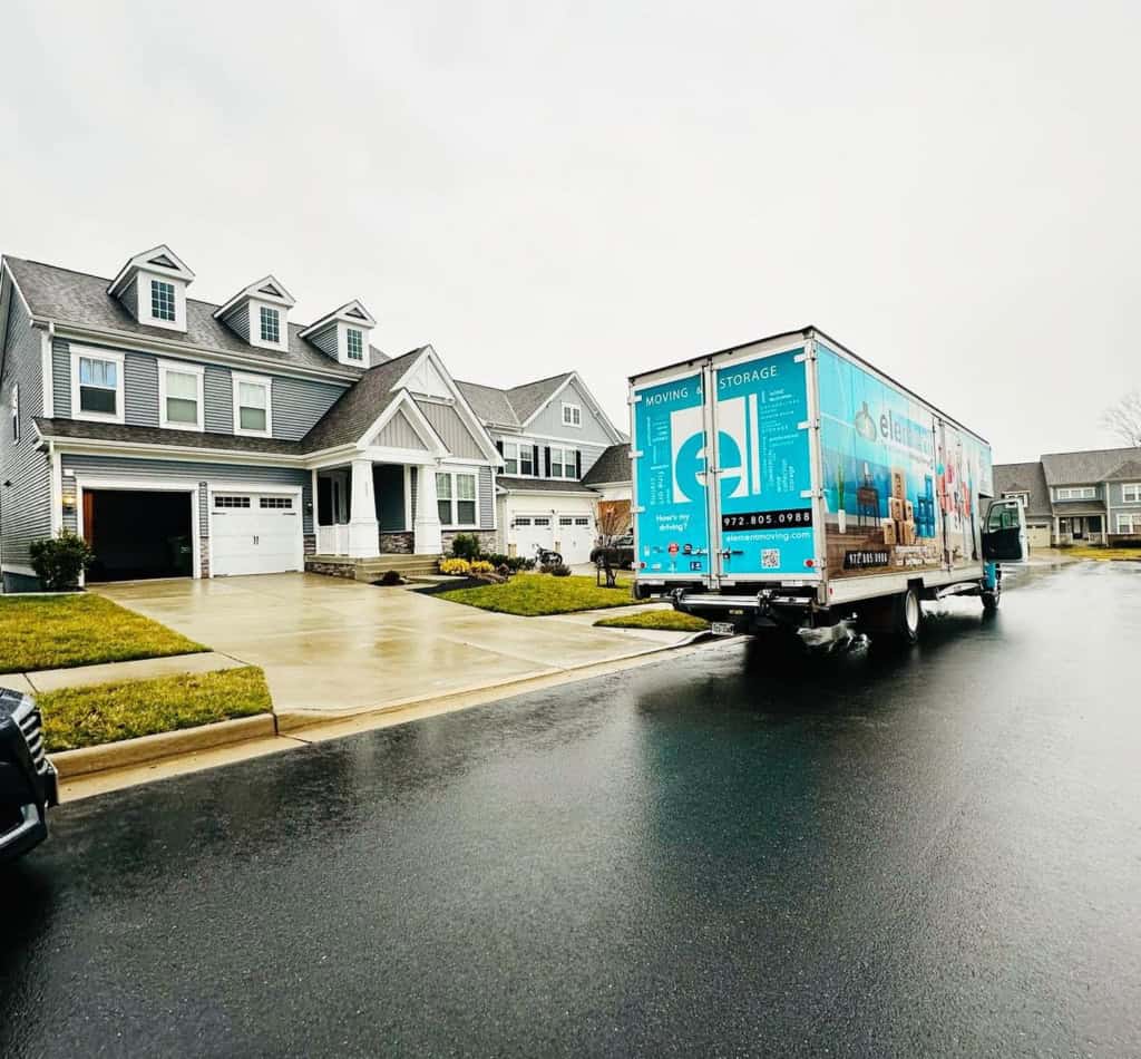 Element moving truck parked on a wet street in front of a suburban house