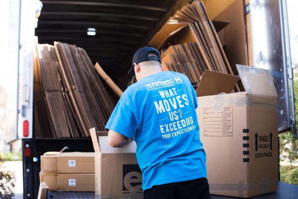 Mover in an Element shirt unloading cardboard boxes from the back of a truck