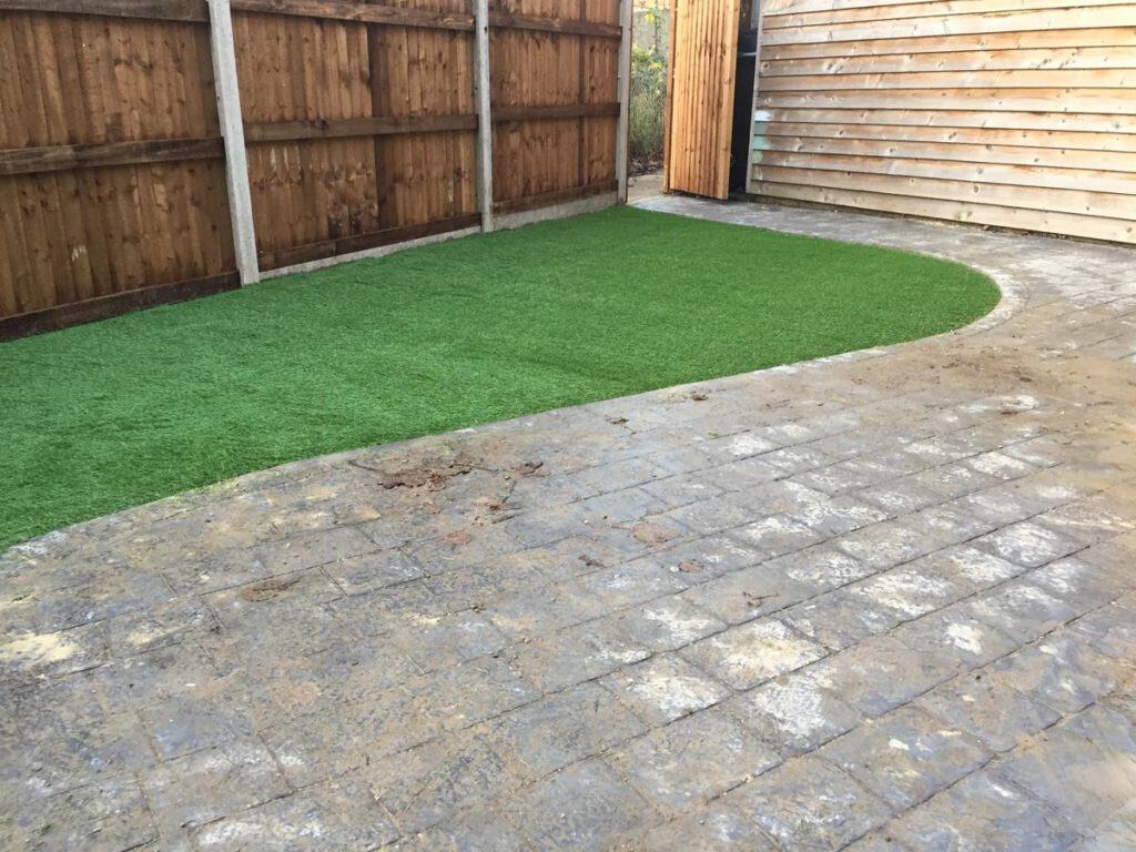 Artificial grass lawn installed in Suffolk garden with wooden fencing.