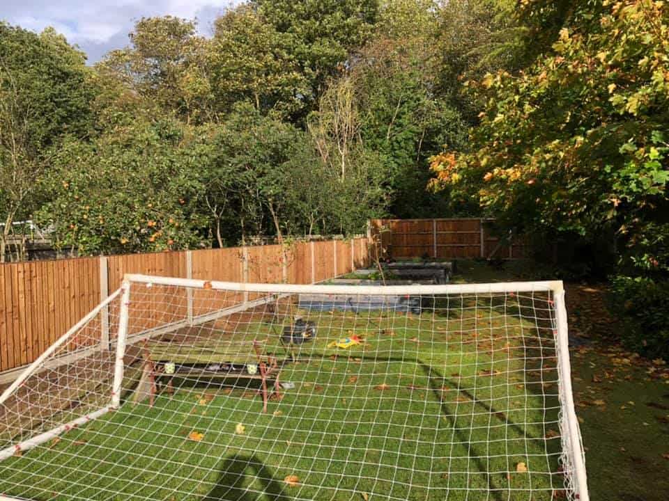 Garden with soccer goal, trees, and wooden fence in autumn.