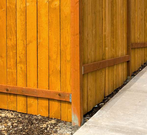 Close-up of a wooden garden fence with a concrete path.